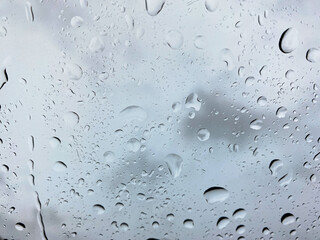 Full frame of drops and splashes of raindrops with cloudy sky at the background