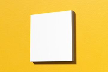 White square canvas hanging on yellow wall, creating a modern art mockup