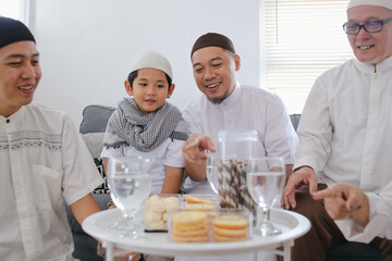 Multi Generation Muslim Family Enjoy Eating Snacks and Cookies Together During Eid Mubarak in The Living Room