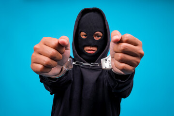 Hooded Thief With Handcuffs Isolated On Blue Background