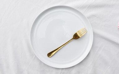 A plain ceramic plate resting on a fabric table cloth, symbolizing simplicity and restriction, representing diet and mindful eating.