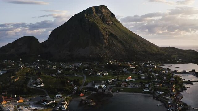 Aerial drone shot flying back to reveal the Island of Lovund with the summit of Lovundfjellet towering over the village. Lovund, Norway