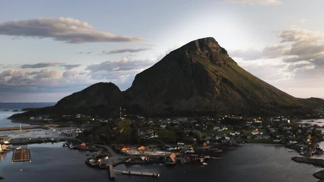 Aerial drone shot flying towards the Island of Lovund with the summit of Lovundfjellet towering over the village. Lovund, Norway