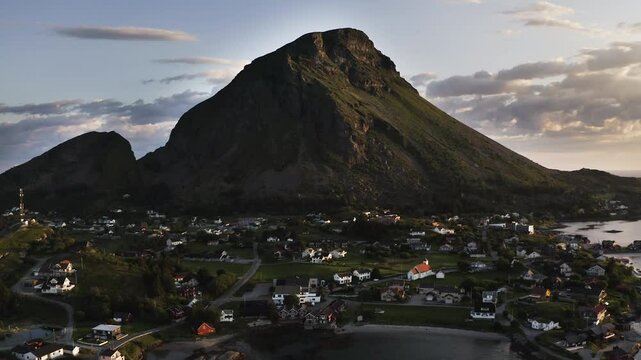 Aerial drone shot panning to the right showing the Island of Lovund with the summit of Lovundfjellet towering over the village. Lovund, Norway