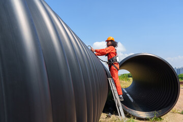 A black female mechanical engineer in a safety uniform inspects and inspects piping systems for a...