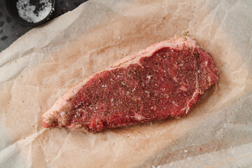 Top view of raw seasoned new york steak on concrete countertop background