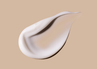 smear of creamy white texture cosmetic sample close up on beige background