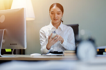 Young adorable Asian businesswoman working with work document during the night, working overtime at...