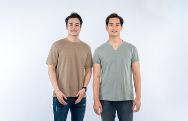 Two smiling men pose in front of a white backdrop, wearing casual t-shirts and jeans, creating a...
