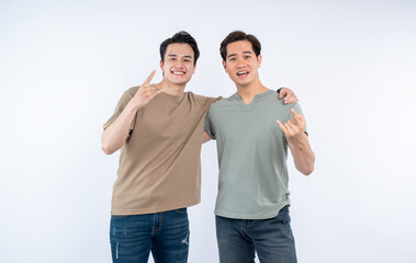 Two smiling men pose together against a white background, each making hand gestures of peace and rock and roll.