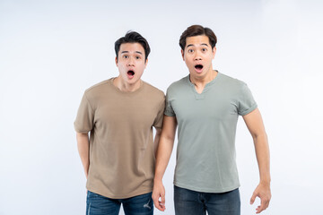 Two young men, mouths agape, express shocked surprise against a clean, white backdrop, their faces mirroring a shared astonishment.
