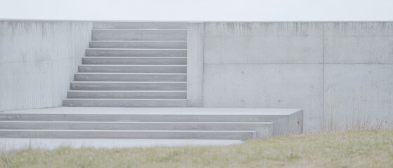 Steps leading to a minimalist concrete wall in an open grassy area