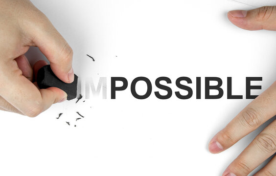 Top view of hand using eraser to erase the word IM in front of word POSSIBLE on paper to change the meaning. Business mindset concept, inspiration and determination to make your goals successful.