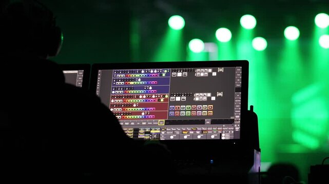 A detailed view of a lighting control panel used for managing stage lights during a live concert, with green stage lights in the background. Music concert. 4k video