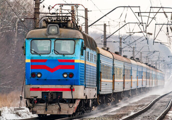 Passenger train rapidly moving along snow covered tracks in Kyiv Oblast of Ukraine