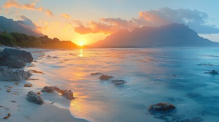 Fototapeta premium Sunlight at sunrise casts long shadows over mountain peaks, illuminating tranquil ocean waters below, creating a serene landscape.