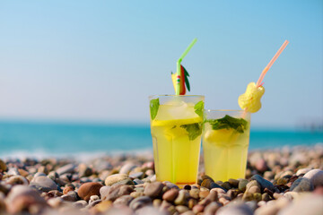 Cocktails with straws and garnishes placed on rocky beach surrounded by nature inspire relaxing seaside moments and tropical enjoyment