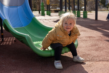 Child enjoys playful time on colorful slides at a playground during a sunny day