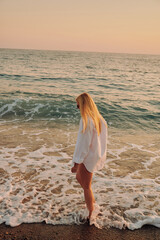 Confident female in swimwear enjoying sunset walk near sea. Dreamy seaside scenery, soft light, and relaxing summer energy. Great for tropical destinations, freedom, and adventure visuals.