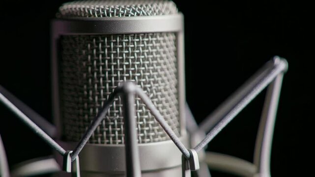 Close-Up of a Silver Condenser Microphone Designed for Professional Audio Recording in a Studio Setting, Highlighting Intricate Mesh and Mounting Details