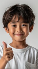 Young child with a joyful expression giving a thumbs up in a light-colored setting