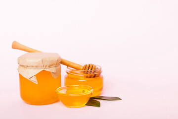 Honey in jar with leaves and honey dipper on colored background top view with copy text