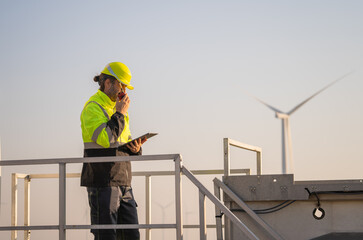 Engineer man working with tablet at windmill farm Generating electricity clean energy. Wind turbine farm generator by alternative green energy.
