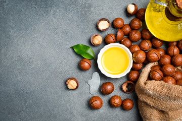 Bowl of macadamia nut oil and macadamia nuts on gray concrete background. superfood and healthy food concept, top view