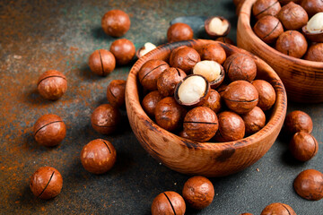 Wooden bowl filled with macadamia nuts. Roasted delicious nuts. Top view.