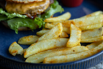 Freshly made cheeseburger served with crispy fries on a blue plate