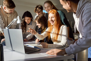 Young business coworkers, happy friendly discussion, students using laptop online at work table, talking discussing project ideas for learning strategy, planning Internet startup, studying together