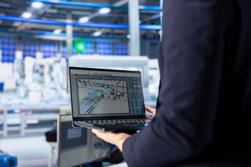Fototapeta premium Engineer in photovoltaics factory using tracking software on laptop to diagnose malfunctioning systems. Solar panels manufacturing plant worker uses notebook to reduce downtime