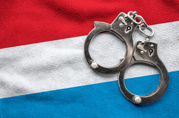 Flag of Luxembourg and police handcuffs. Crime and offenses in country Concept
