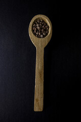 Cucchiaio di legno pieno di lenticchie su sfondo nero elegante.