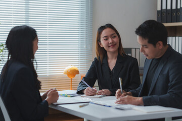Business team working together on a project, taking notes and smiling during a meeting in the office