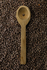 Un cucchiaio di legno con una lenticchia su sfondo di lenticchie.