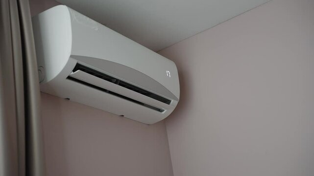 Woman holding air conditioner remote control and setting cooling temperature on split system to 17 degrees, in hotel room, at home. Concept of air cooling in hot room, climate control at home