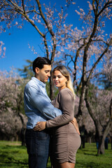 Latin couple embracing in blooming orchard, celebrating love and new life