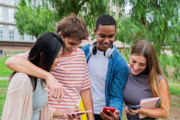 Group of enthusiastic young friends sharing joyful moments while engaging with their smartphones in a lively outdoor environment filled with excitement and laughter among college students