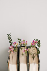 Old books on a desk with flowers and leaves, grey background