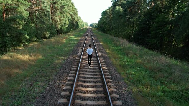 beautiful girl walking on railway in forest on summer day