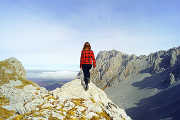 Conquering the peaks: a woman photographed from behind takes the last steps of a hiking route. A...