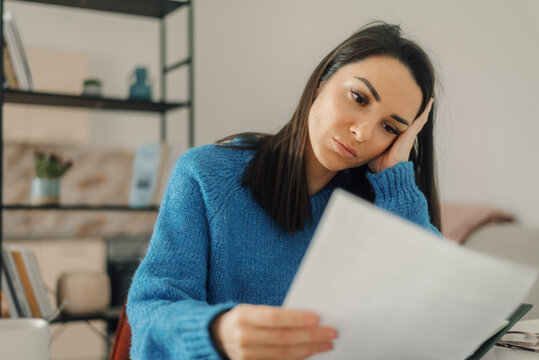 Stressed woman reading negative news in a letter at home