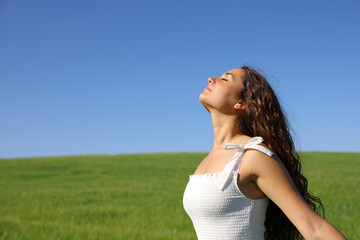 Woman in white dress breathing fresh air in green field