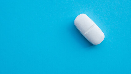 White medicine pill tablet on blue background