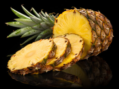 tropical pineapple, sliced fruit, vibrant yellow flesh, green spiky leaves, ripe and juicy, dark background, high contrast, food photography, closeup, glossy surface, fresh produce, exotic fruit, culi