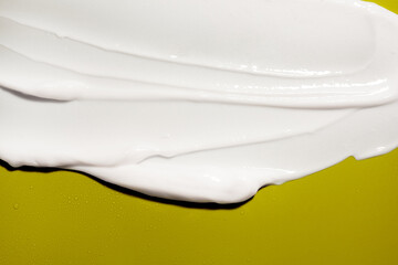 Face or body white cream hair balm or melted wax on yellow green background
