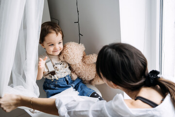 Toddler holding a toy bear while interacting with mother. Comfort objects, teddy bear significance,...