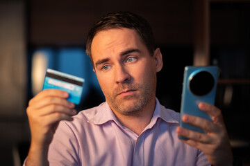 Online payment concept. Man using credit card with mobile phone at white background. Male hands holding smartphone with blank screen and reverse bank card. Person pays using mobile. Transaction.
