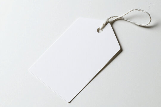 Blank white tag with string on a light background for customizable labeling. isolated on white background.